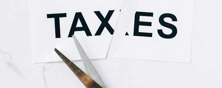 image of scissors cutting the paper with taxes written on it